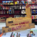 Raw rolling paper boxes on a display with a store shelf in the background--20 pack of original classic raw lean cones