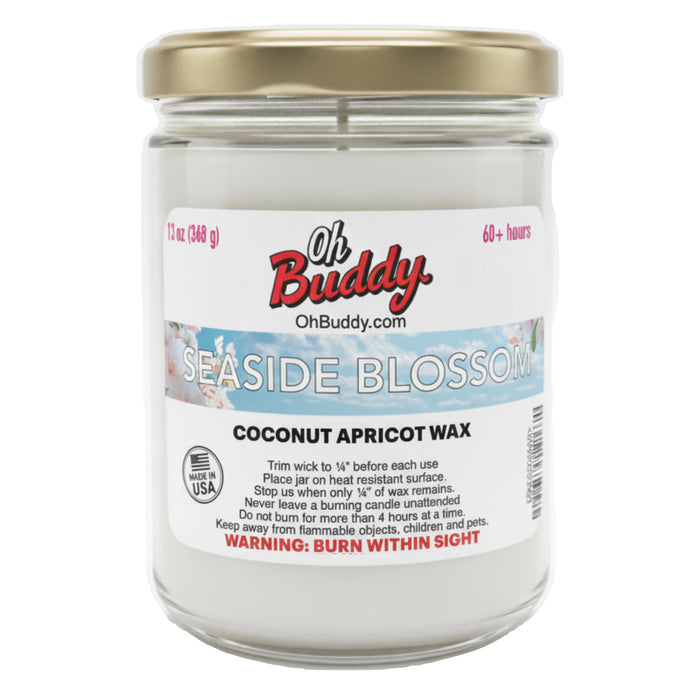 Jar of Oh Buddy candle labeled 'Seaside Blossom' with a gold lid on a white background